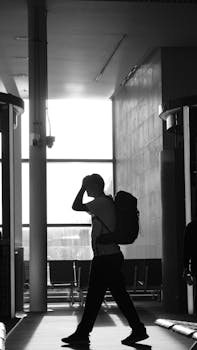 Silhouette of a man walking with a backpack at an airport terminal.