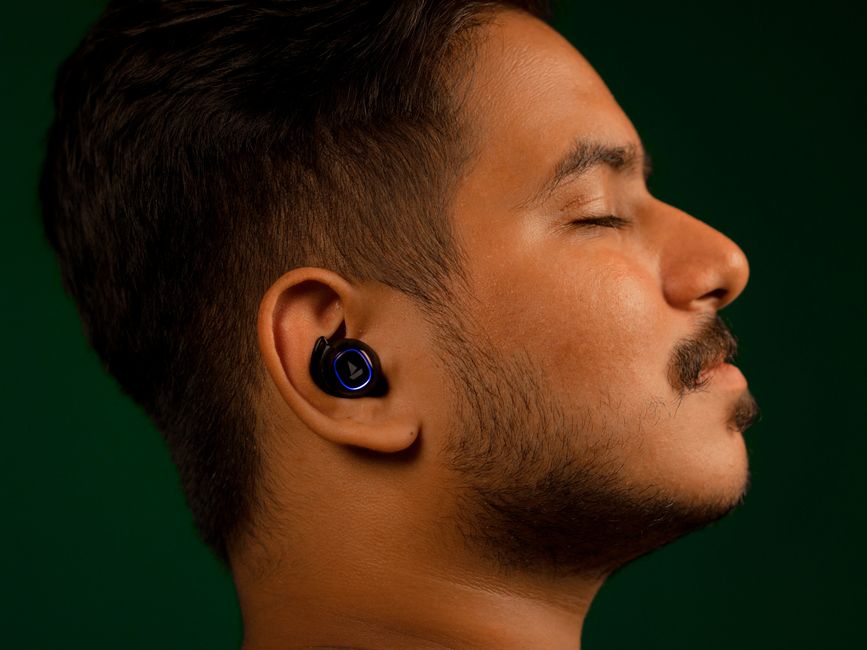 Close-up of a man listening to music with earbuds, eyes closed, serene expression.