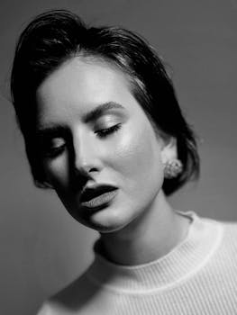 Sophisticated black and white portrait of a woman with eyes closed, conveying elegance.