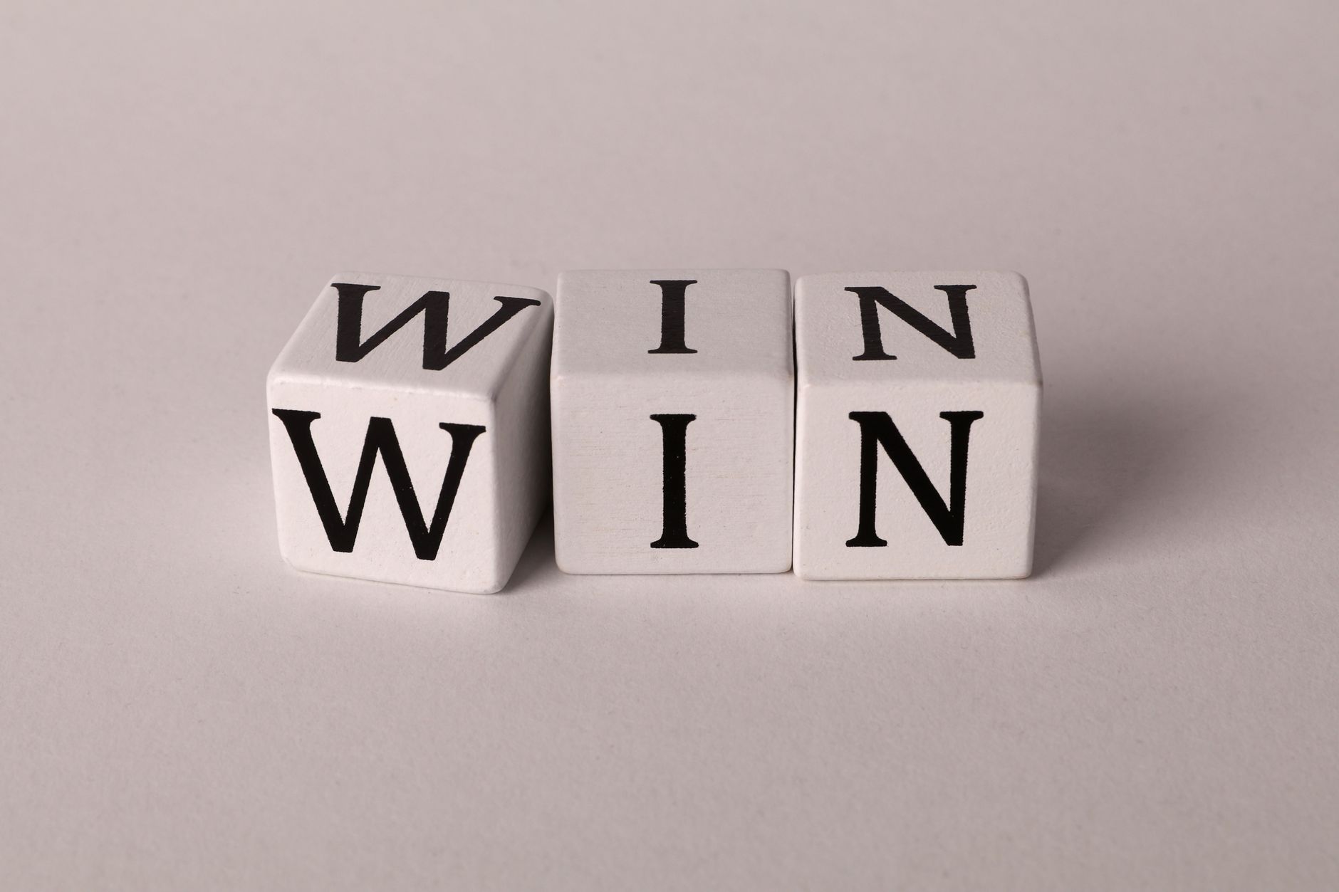 White cubes with the word 'WIN' against a light background symbolizing success and achievement.