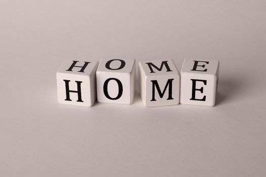 Close-up of white dice forming the word HOME on a neutral background.