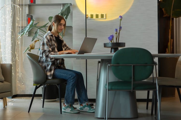 Woman Sitting By Table And Working On Laptop