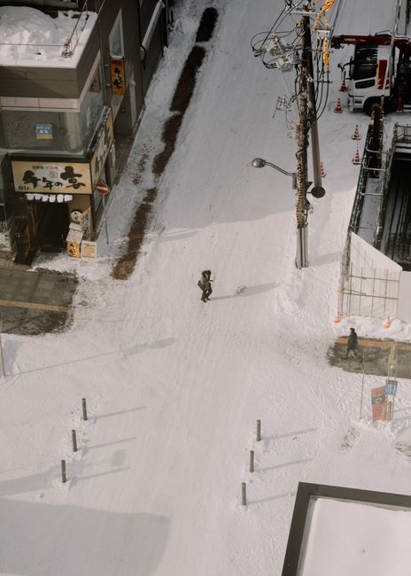 Snowy crossroad in Hokkaido, Japan captured from above, highlighting winter city life.