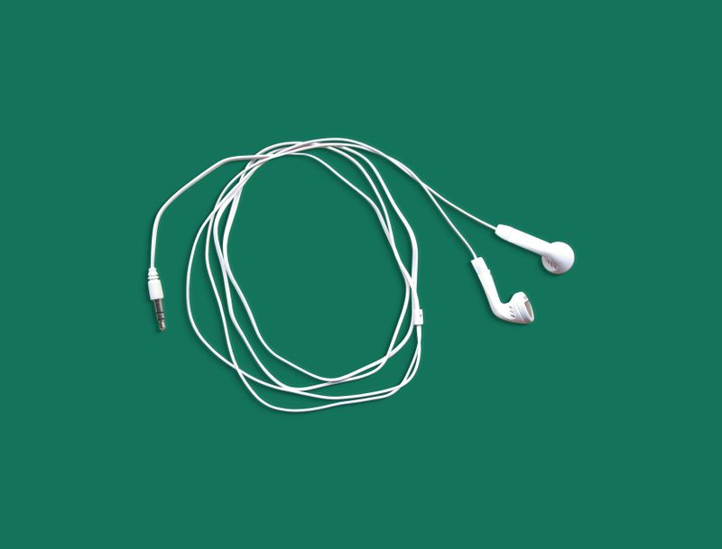 White earphones coiled on a bright green background