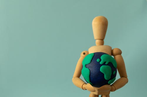 Plasticine Earth in the Hands of a Wooden Puppet