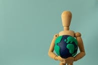 Plasticine Earth in the Hands of a Wooden Puppet
