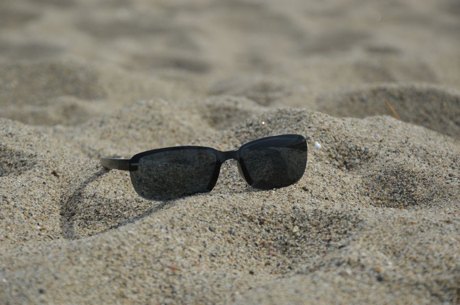 Close-up of sunglasses on sand, perfect for beach and summer themes.