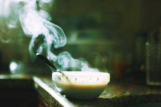 A steaming bowl of soup sits on a kitchen counter, emitting warm wafts into the air.