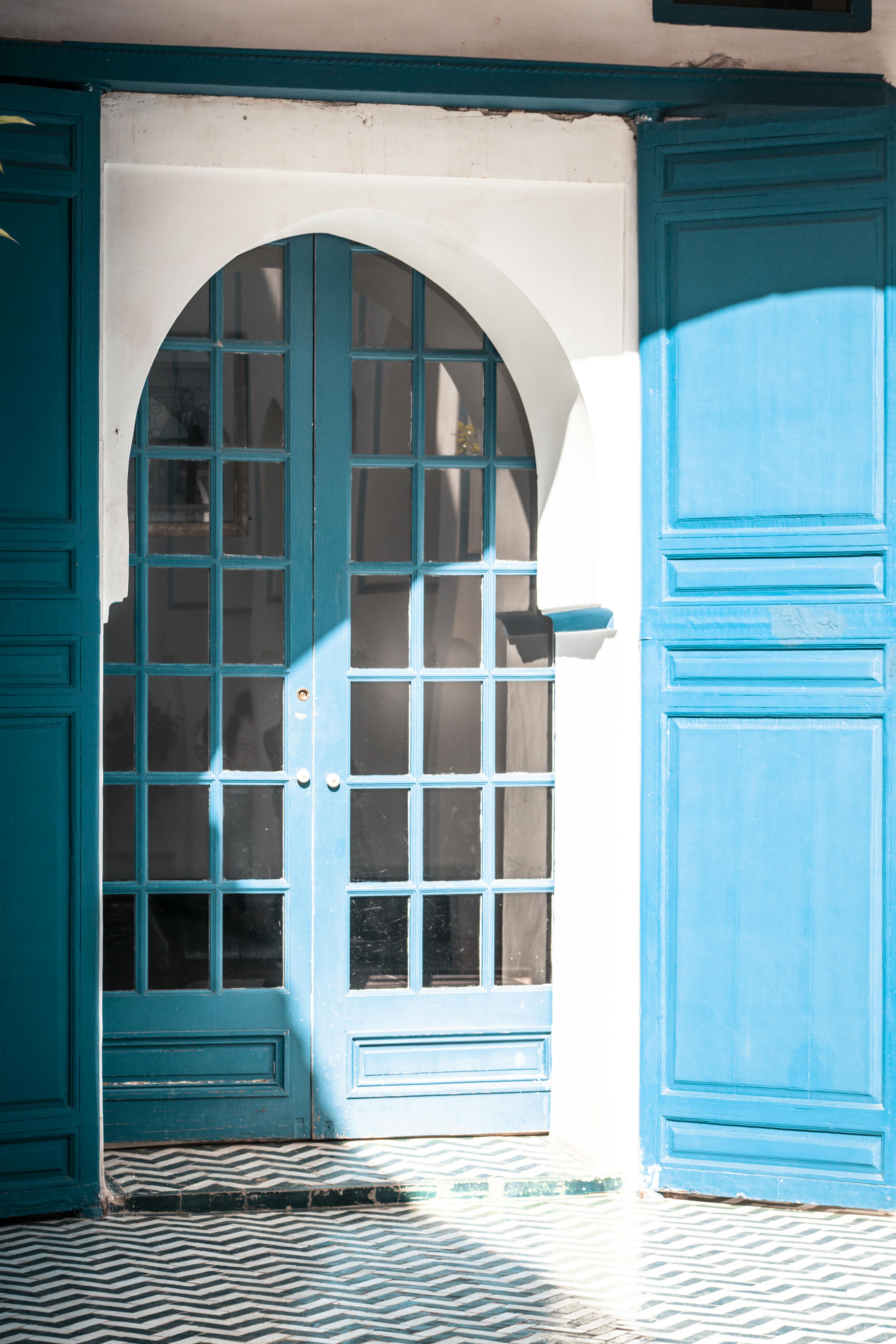 Elegant blue arched French doors with intricate patterns in Marrakech, Morocco.