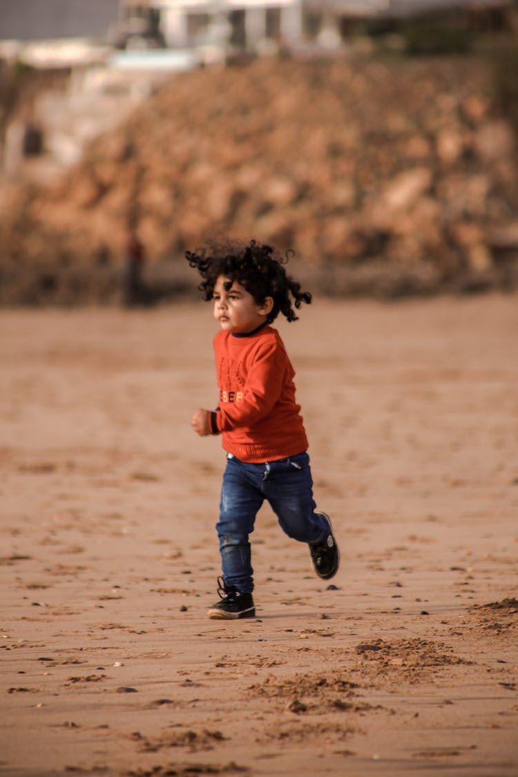 Child In A Red Shirt Running On The Beach