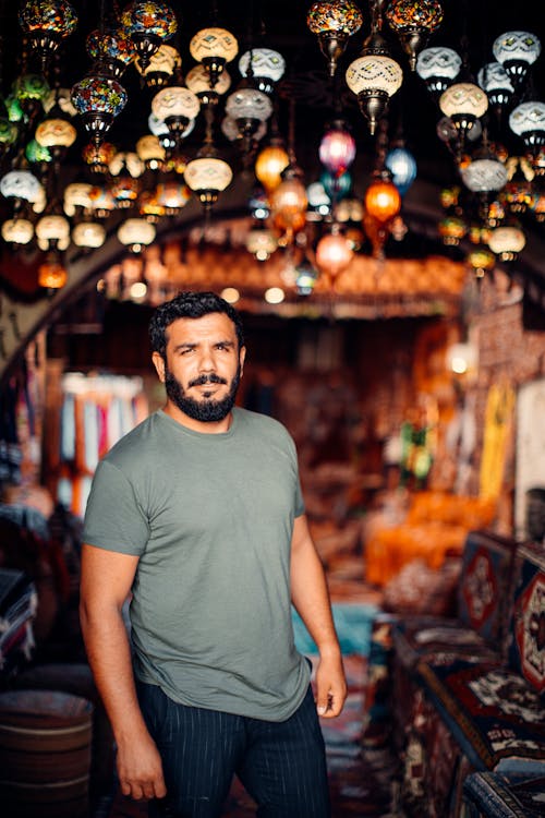 Man Standing on Bazaar under Ornate Lamps