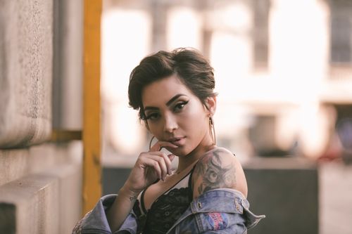 Free Chic fashion portrait of a woman posing outdoors in a denim jacket, showcasing modern urban style. Stock Photo