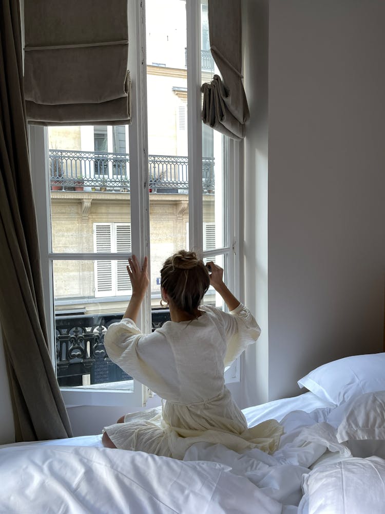 Woman Opening Window In Bedroom