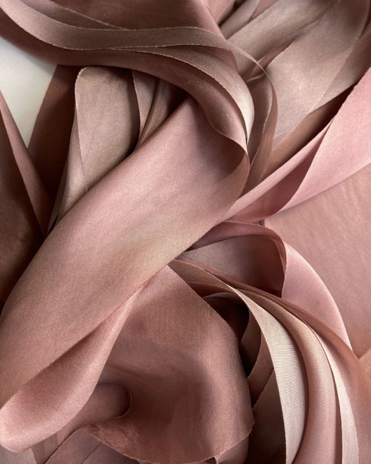 Close-up of elegant pink silk fabric with flowing folds and soft texture, perfect for textile and design projects.