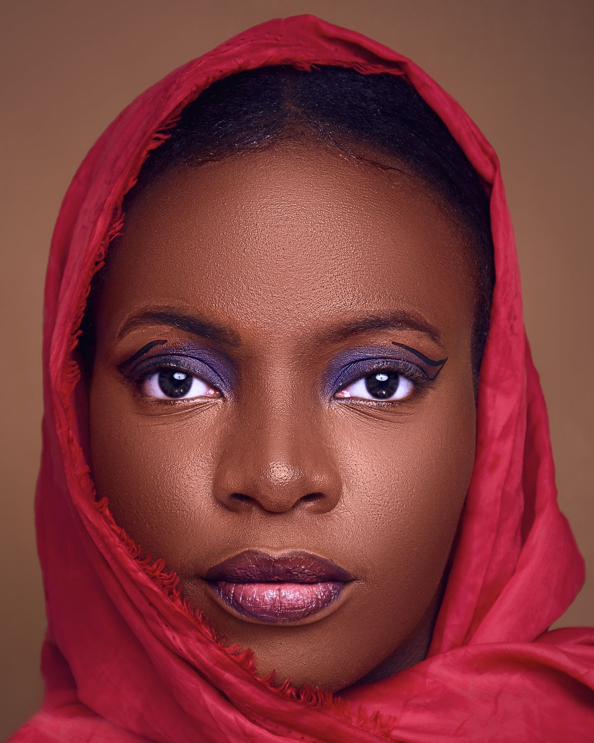 Studio portrait with deep brown eyes, violet shadow and red headscarf