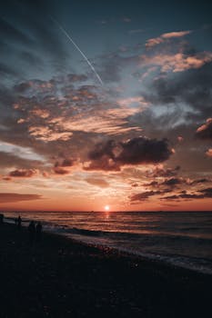 Peaceful sunset at Batumi Beach with silhouetted figures against a dramatic sky over the Black Sea.