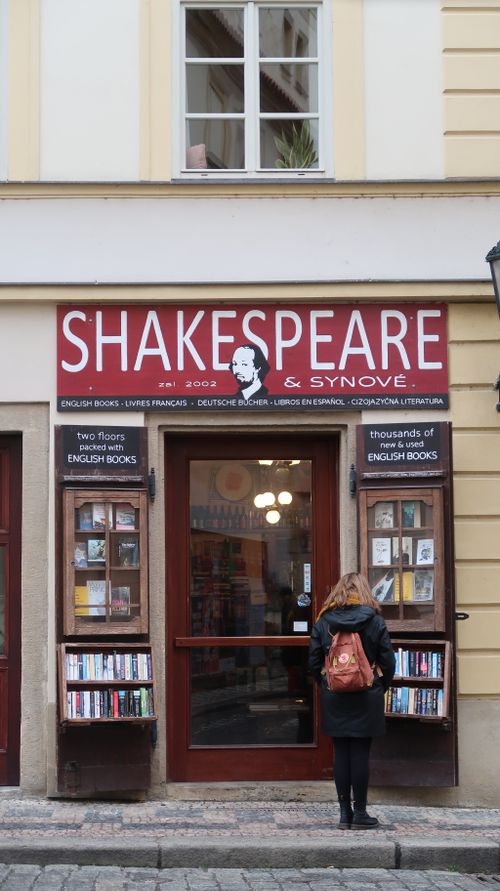 Free A woman stands outside a charming Prague bookstore featuring Shakespeare-themed signage. Stock Photo