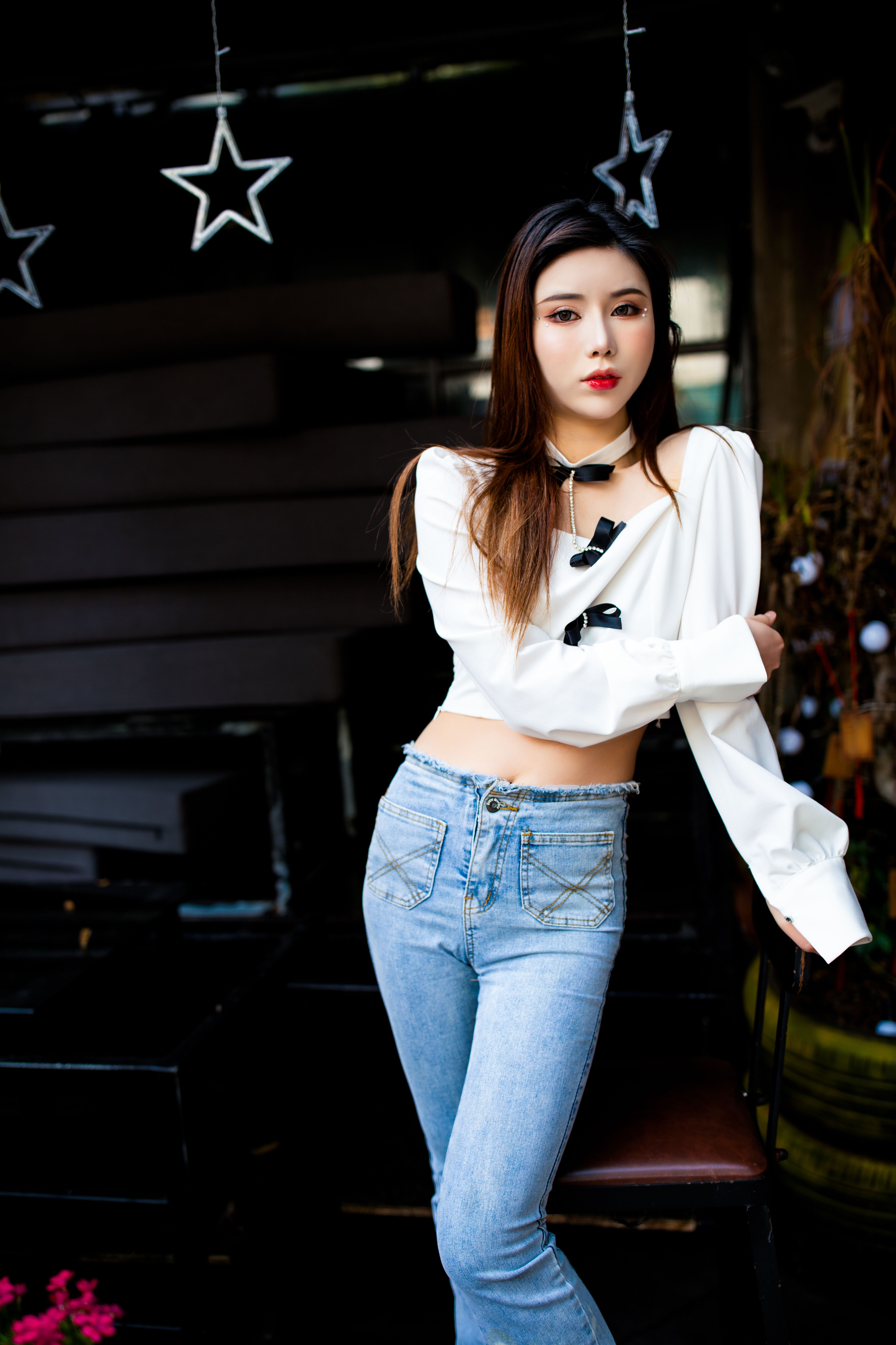 Fashion-forward young woman in chic blouse and jeans, striking a pose.