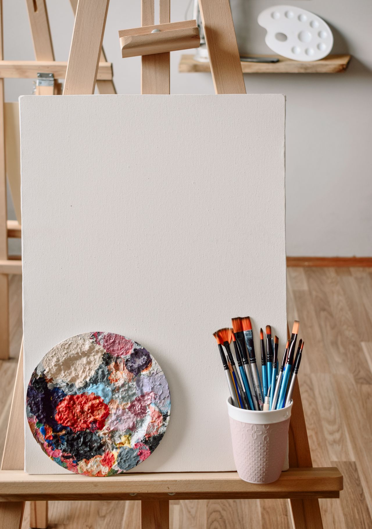 Bright studio with a blank canvas on an easel with a palette and paint brushes, symbolizing the start of the journey