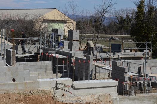 Construction workers building a concrete structure at a sunlit site.
