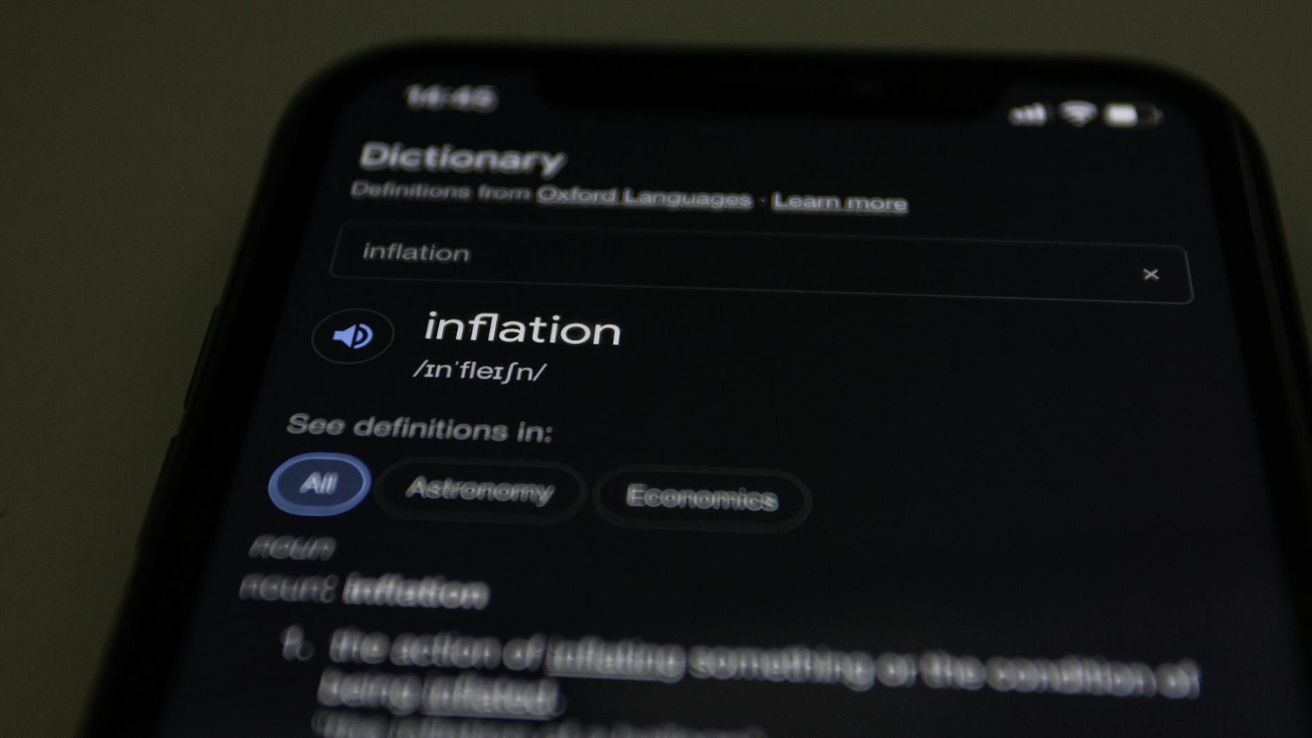 Close-up of a smartphone screen showing the word inflation defined in a dictionary app.