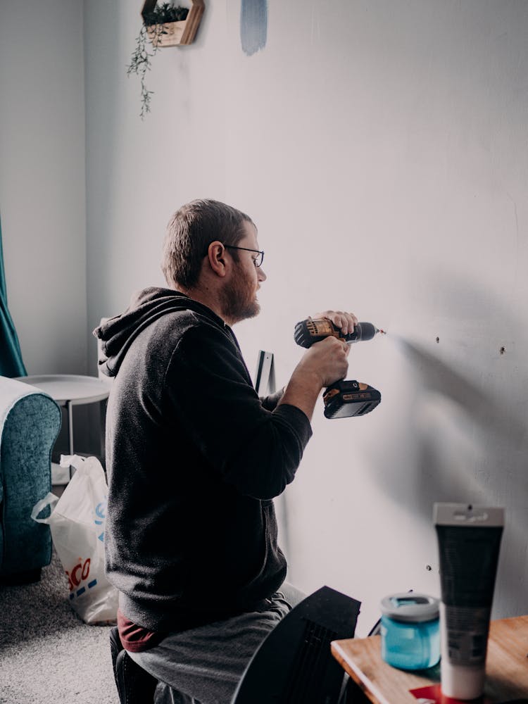 Man Drilling In Wall In Home