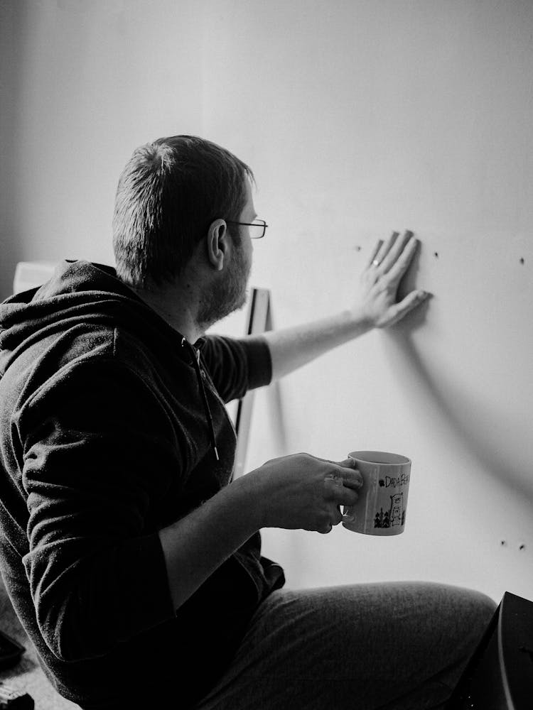 Man With Cup Near House Wall