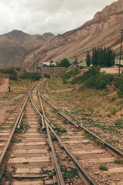 Free Rustic railway tracks stretch through a serene mountain landscape, embracing nature's harmony. Stock Photo