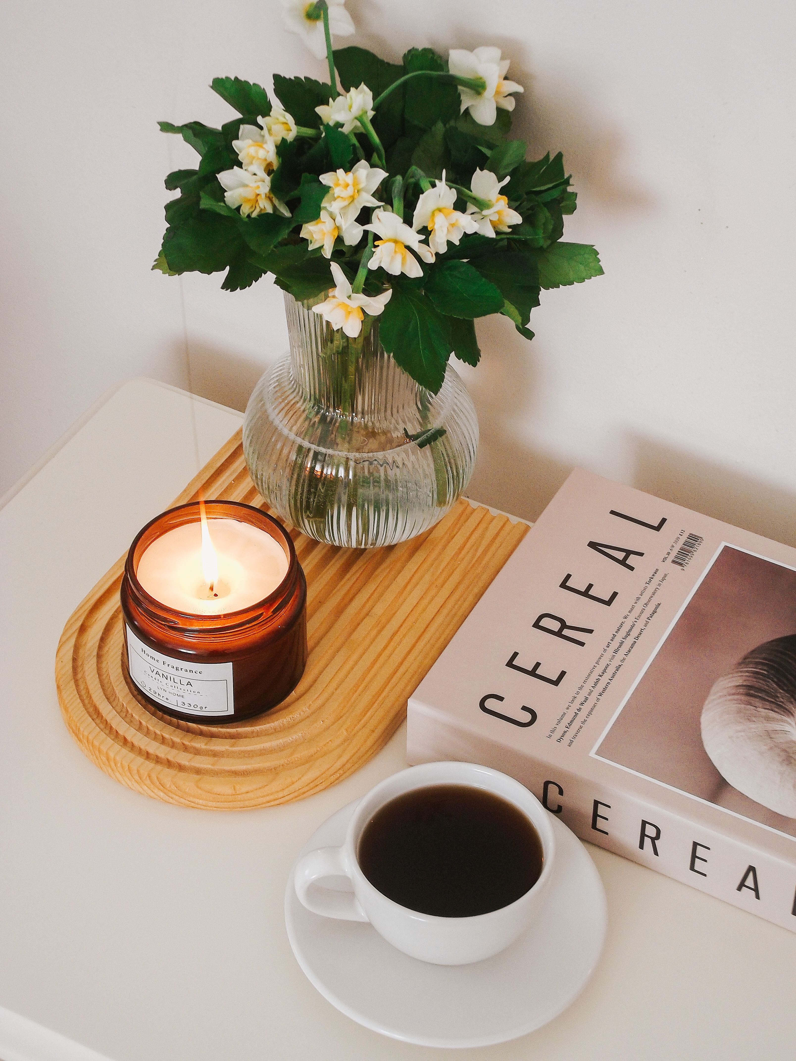 A peaceful setting of coffee, a candle, and flowers perfect for relaxation.