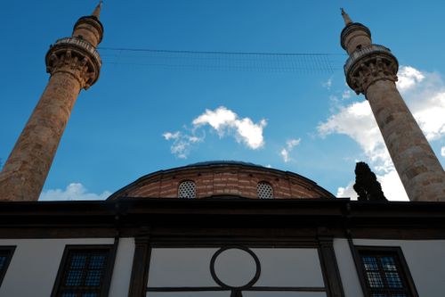 Free A low angle shot of mosque minarets reaching into a clear blue sky with fluffy clouds. Stock Photo