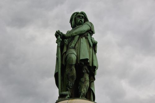 Free A powerful low-angle photograph of the Vercingetorix statue under a dramatic cloudy sky. Stock Photo