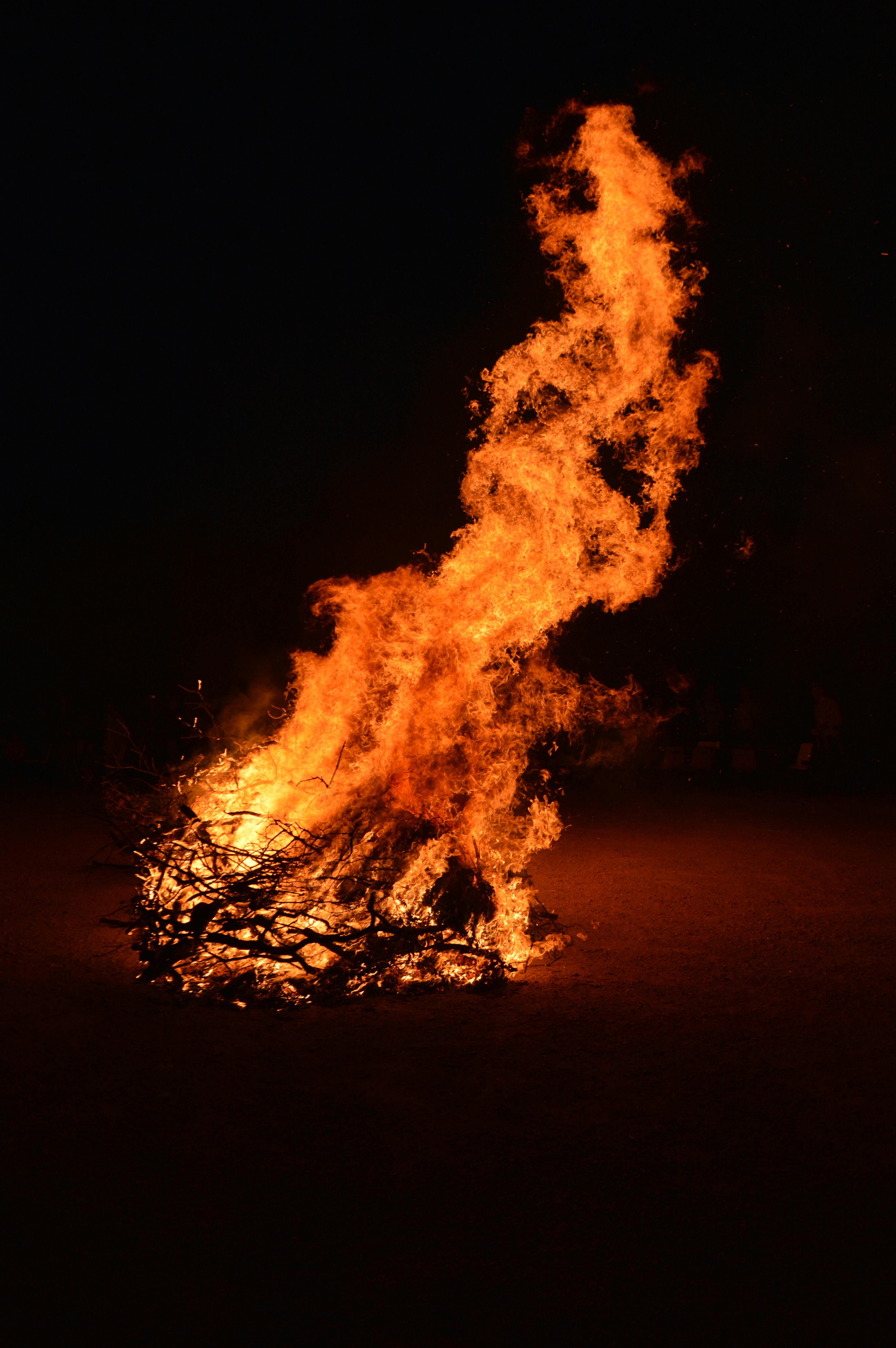 A large bonfire burning with bright flames against a dark night backdrop.