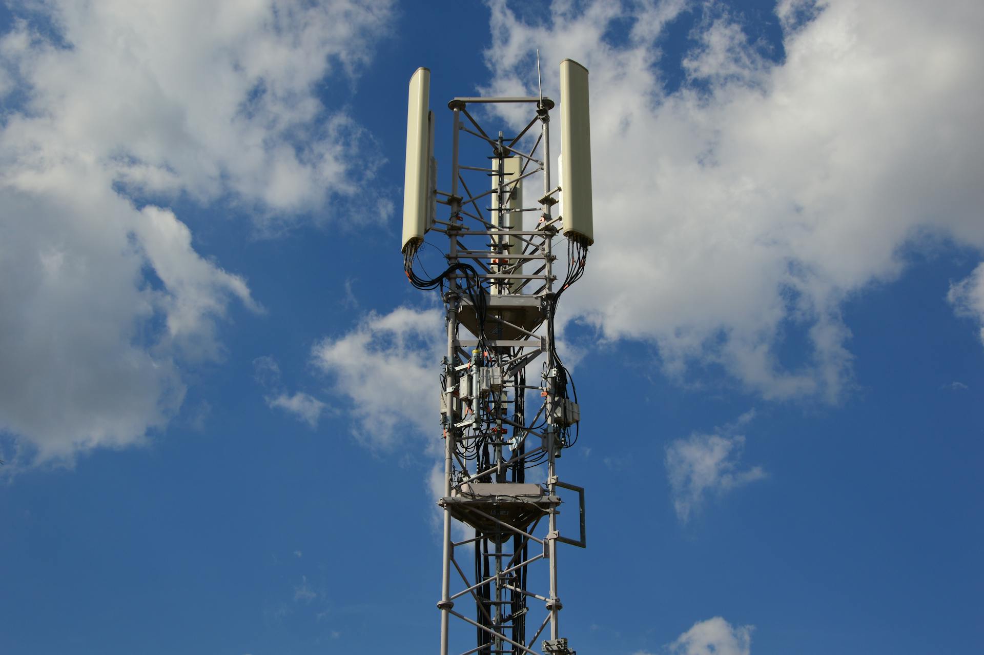 A tall cellular communication tower against a vivid blue sky, symbolizing modern technology.