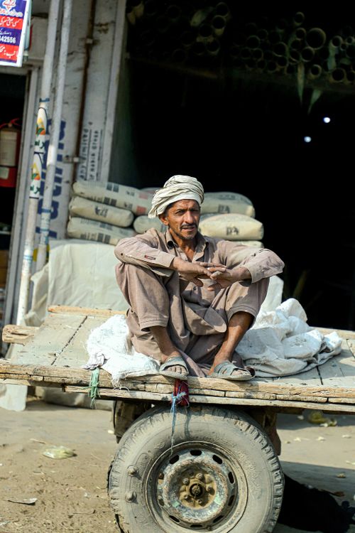 Free A man with a mustache resting on a cart in Bahawalpur street scene. Stock Photo