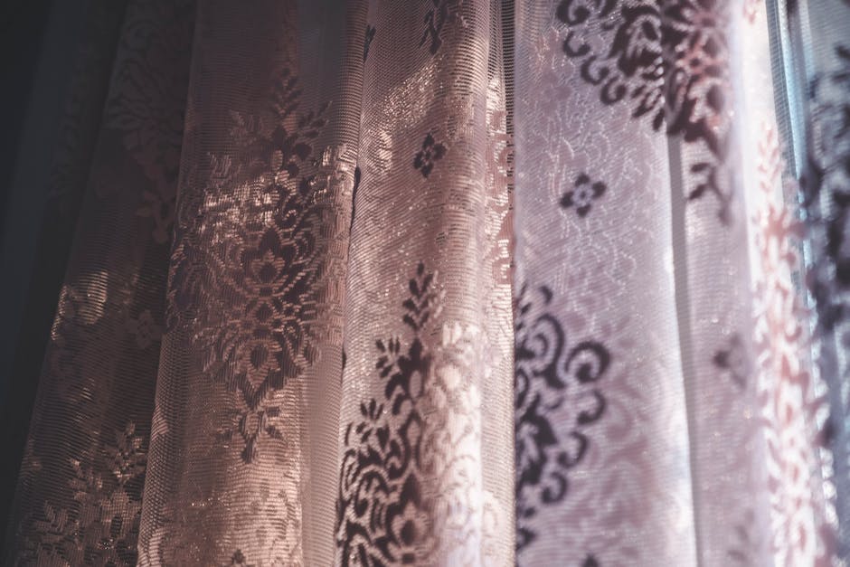 Detal prowadzenia zasłon na szynie sufitowej i równy układ fałd przy oknie