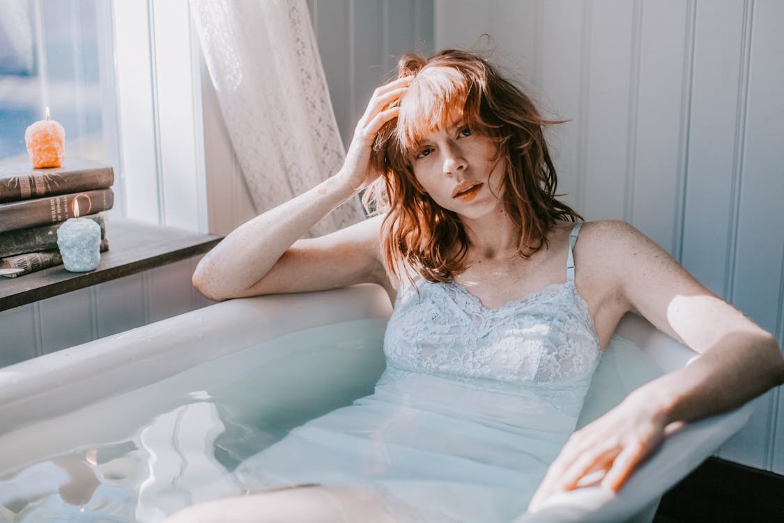 Woman Laying On Bath Tub While Holding Her Head Free Stock Photo