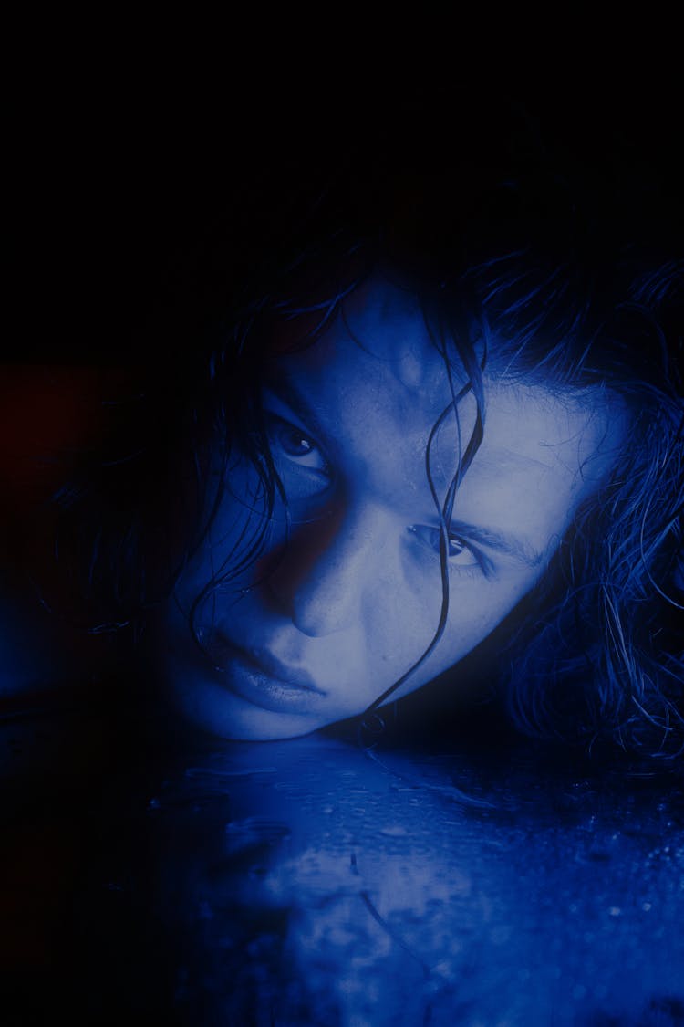 Close-up Of Woman In Blue Light On Face