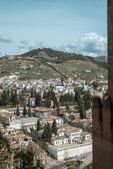 Aerial view of Granada's historic architecture with lush hills in the background.
