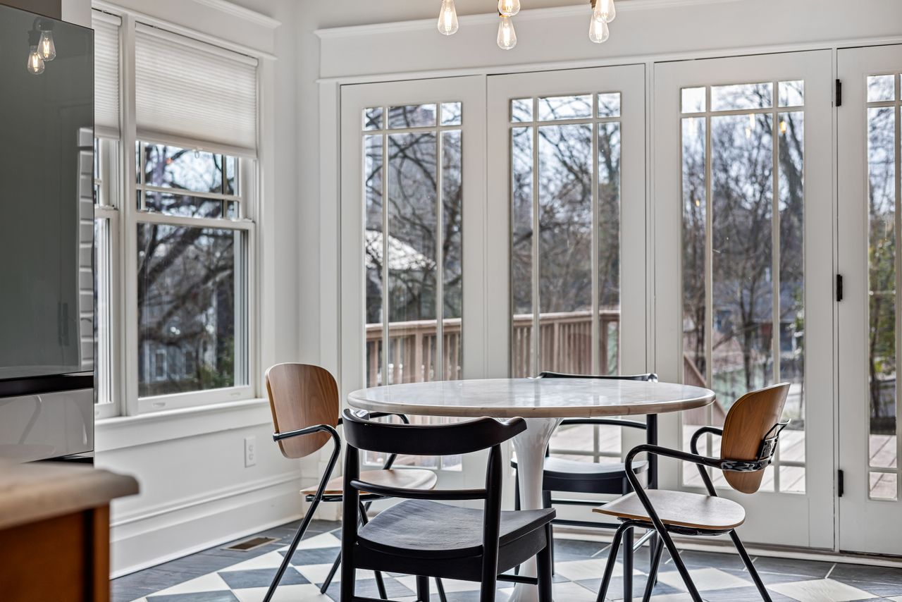 Round white pedestal table with four chairs in a bright sunroom