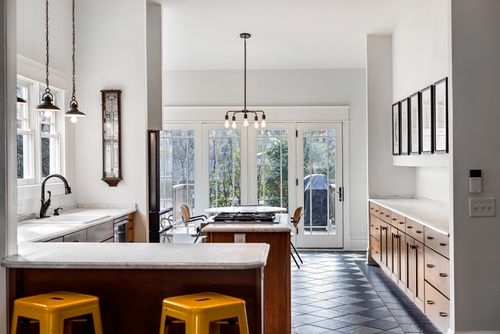 Free Sleek modern kitchen with natural light, white walls, and wooden cabinets for contemporary interior design. Stock Photo