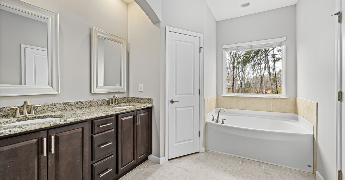 Spacious modern bathroom with granite counters and a large bathtub.