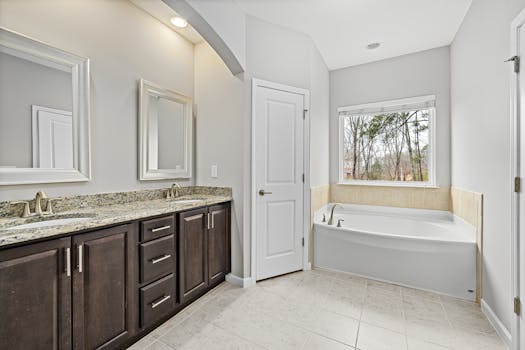 Spacious modern bathroom with granite counters and a large bathtub.