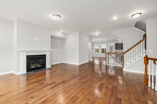 Empty modern living space featuring hardwood floors and a fireplace, ideal for decor inspiration.