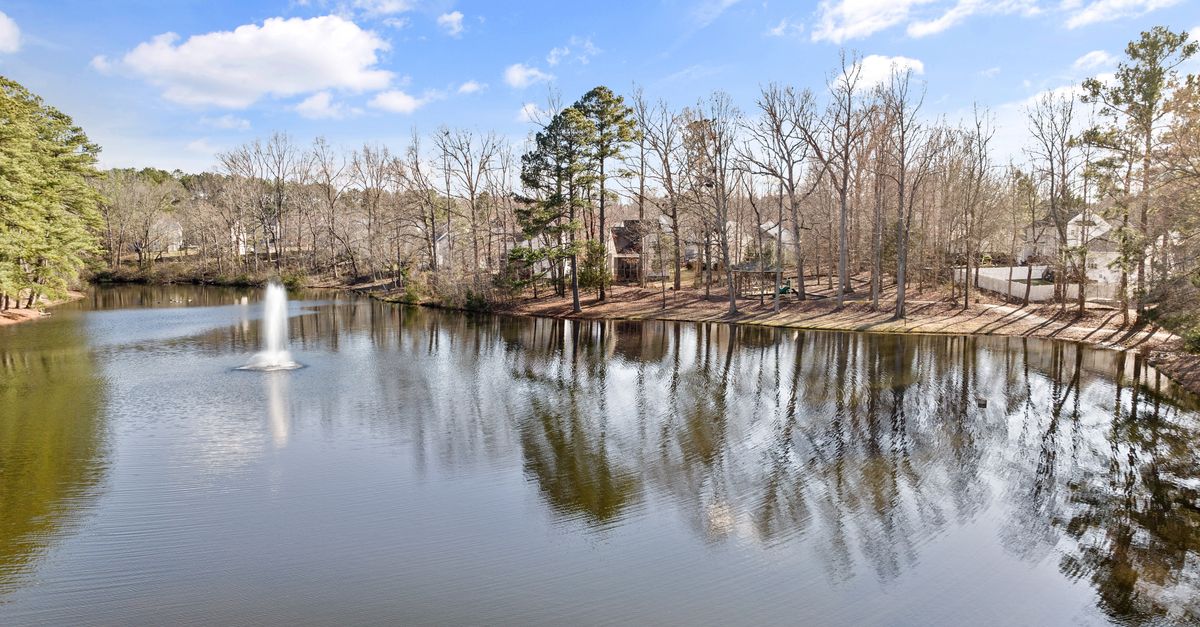 Beautiful lakeside scene in Knightdale, NC featuring a tranquil fountain and bare trees reflecting on the water.
