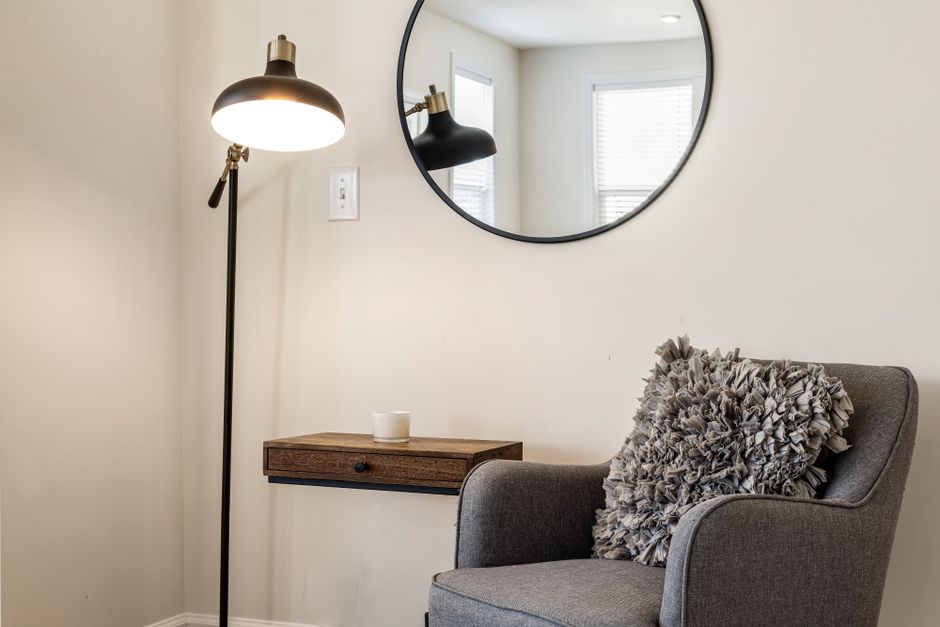 A cozy, minimalist living room drenched in soft natural light, featuring flaxen-colored linen curtains, light oak furniture, and cream-colored plaster walls.