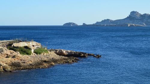 Free Peaceful coastal scene with a rocky shoreline and expansive blue ocean under a clear sky. Stock Photo
