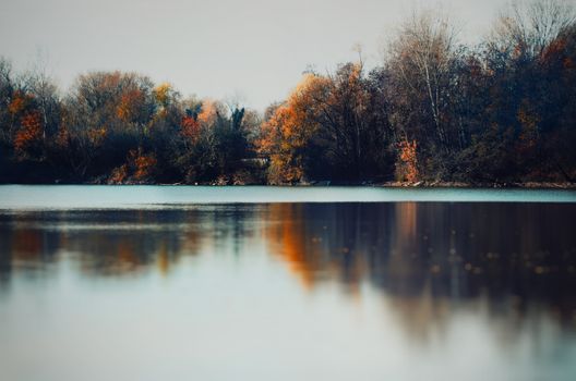 Peaceful autumn scene with colorful trees reflecting in a calm river.