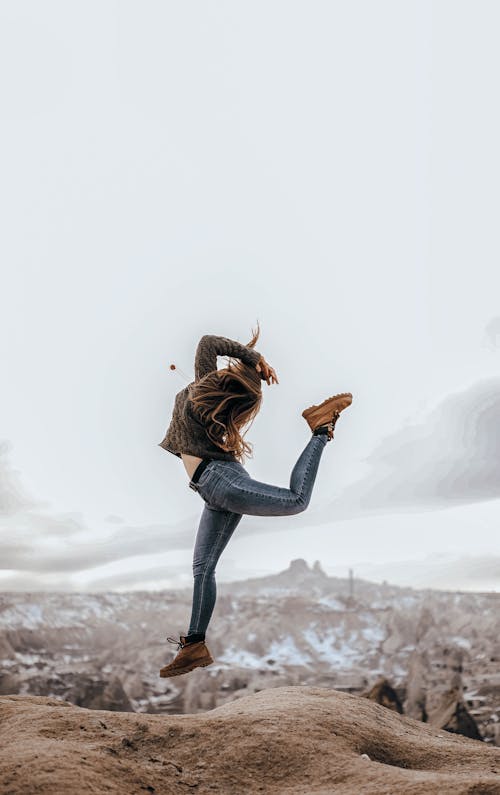 Woman Jumping on Rocks in Mountains Landscape