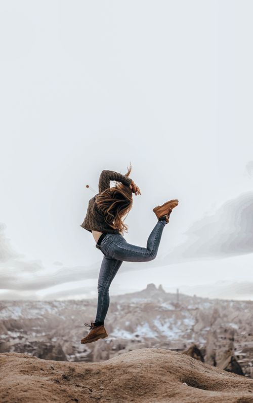 Free A woman performing a dynamic jump against the stunning landscape of Cappadocia, Turkey. Stock Photo