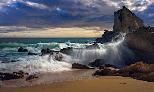 Foto profissional grátis de beira-mar, borrifando, cair da noite